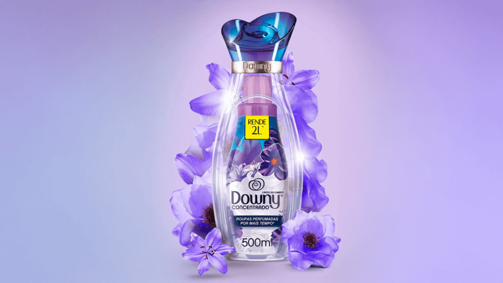 A imagem apresenta o elegante amaciante Downy Lírios do Campo em uma embalagem sofisticada, cercada por delicadas flores lilases que representam suas notas florais suaves e frescas. Com rendimento de 2L a partir de uma embalagem de 500ml, ele é ideal para quem busca perfume duradouro e maciez nas roupas. Uma escolha delicada e envolvente, perfeita para quem deseja o melhor amaciante Downy com fragrância inspiradora e delicada.